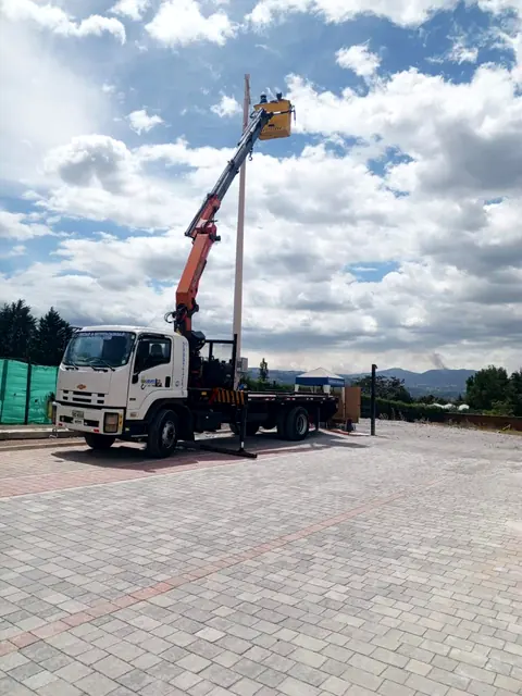Camión grúa con canastilla elevada en un patio adoquinado