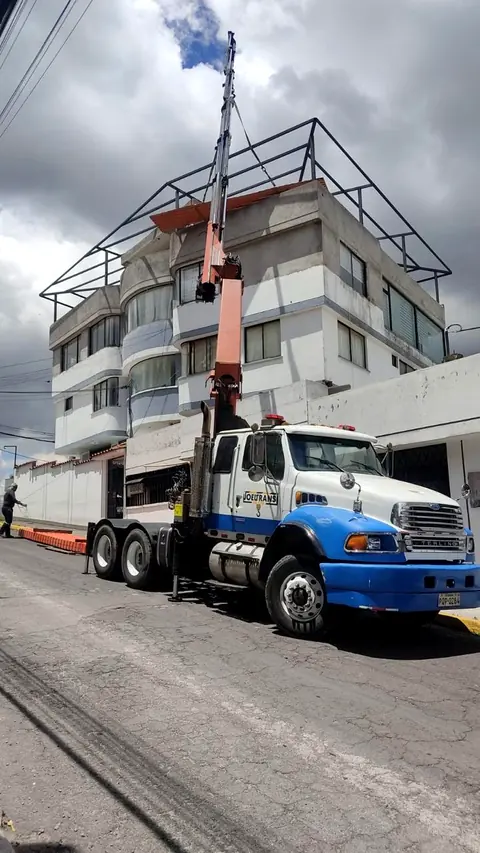 Camión grúa montando una estructura metálica sobre un edificio