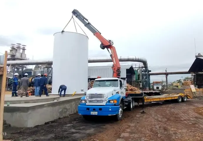 Camión grúa izando un tanque vertical en una planta industrial