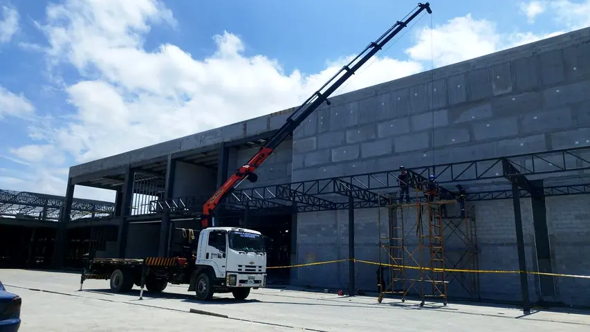 Camión grúa trabajando en una obra junto a una estructura metálica
