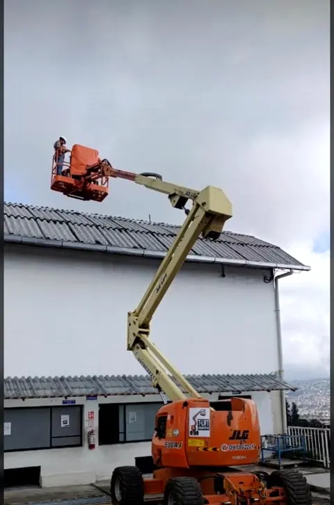 Elevador articulado trabajando en el techo de un galpón