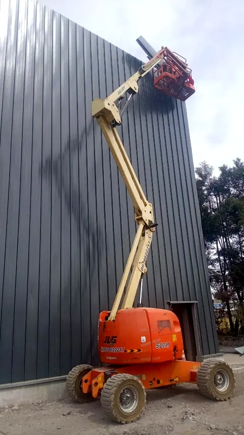 Elevador articulado trabajando junto a una fachada metálica