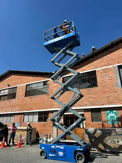 Elevador de tijera elevado junto a una fábrica de ladrillo