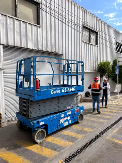 Elevador de tijera listo para trabajar en la entrada de una fábrica