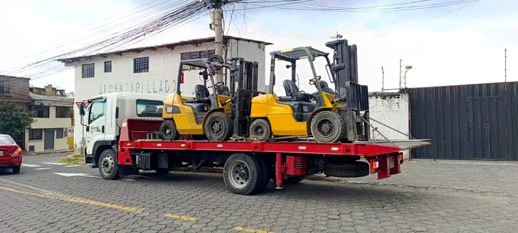 Plataforma transportando dos montacargas amarillos
